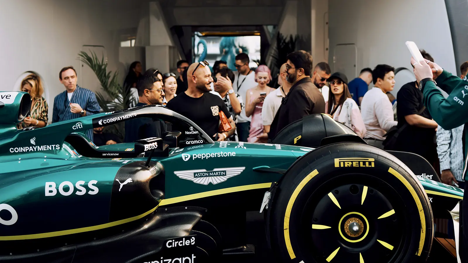Guests around a Formula 1 car exhibited onboard the Ultimate Superyacht